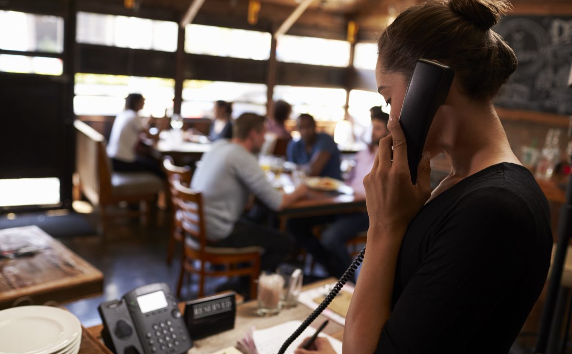 Young,Woman,Taking,A,Reservation,By,Phone,At,A,Restaurant